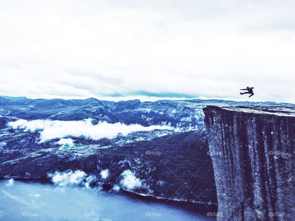 Jumping silhouette on the edge of Prekestolen rock in Norway.