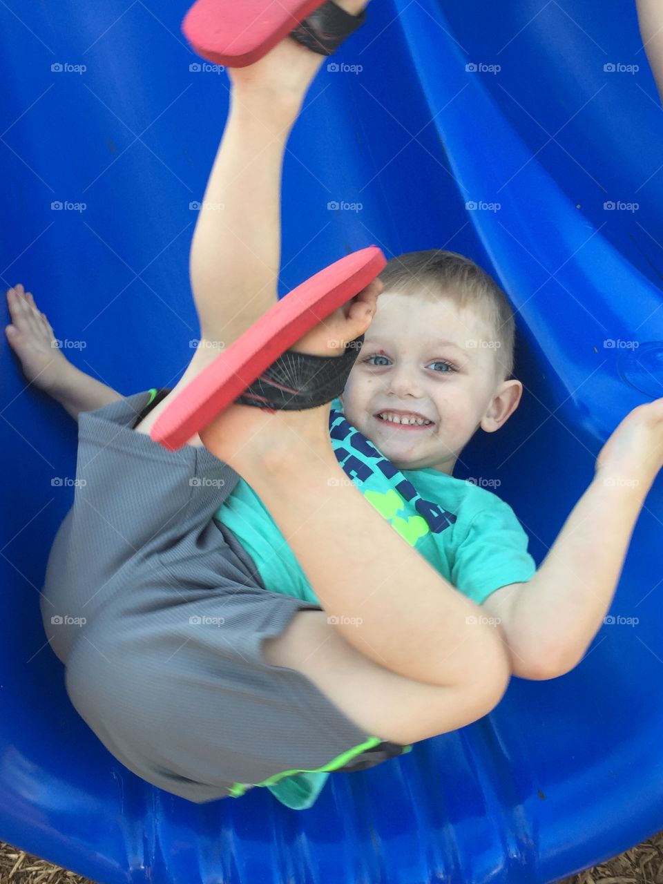 Smiling boy lying on blue slide