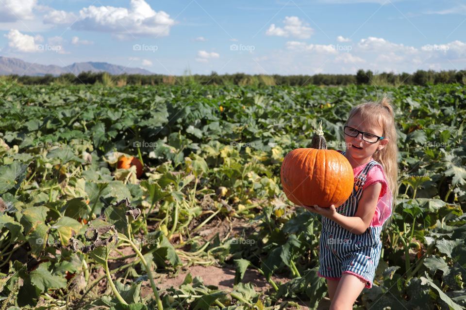 Child carrying a pumpkin