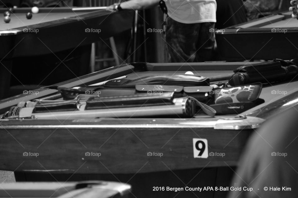 Pool players' pool cues and a pool table in Monochrome