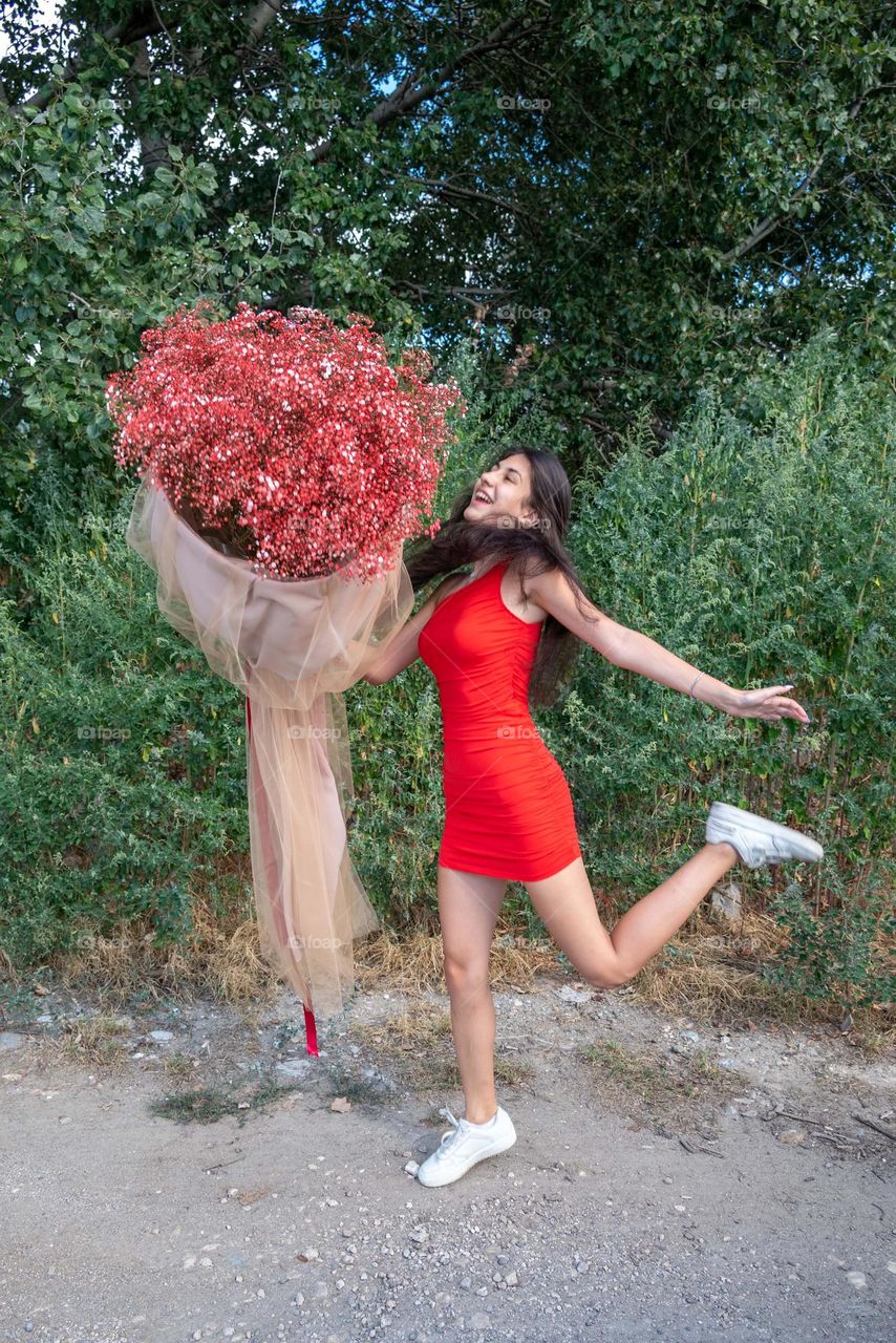 Beautiful Girl Dances with a Large Bouquet of Red Flowers