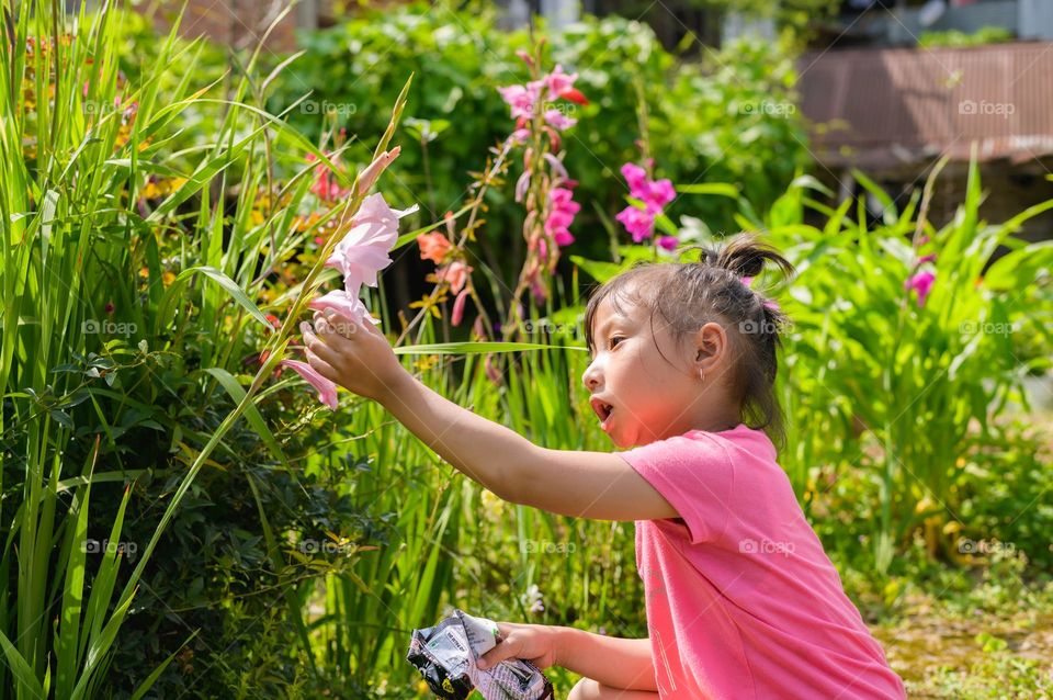 A little girl touching and feeling the blooming of flowers in spring