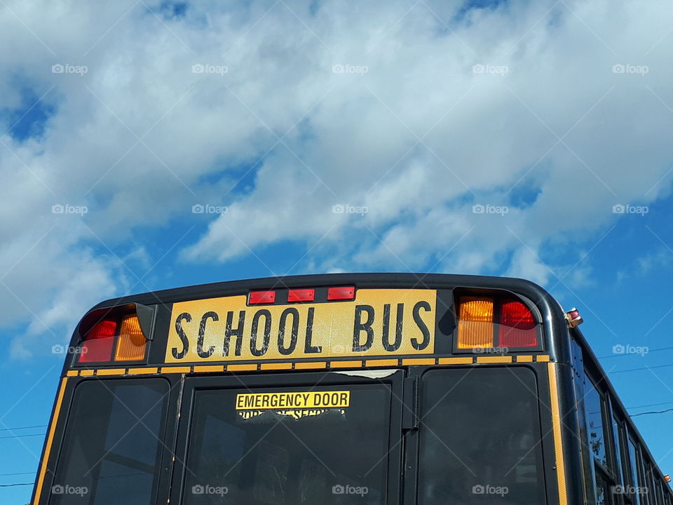 The big yellow school bus against the blue sky.