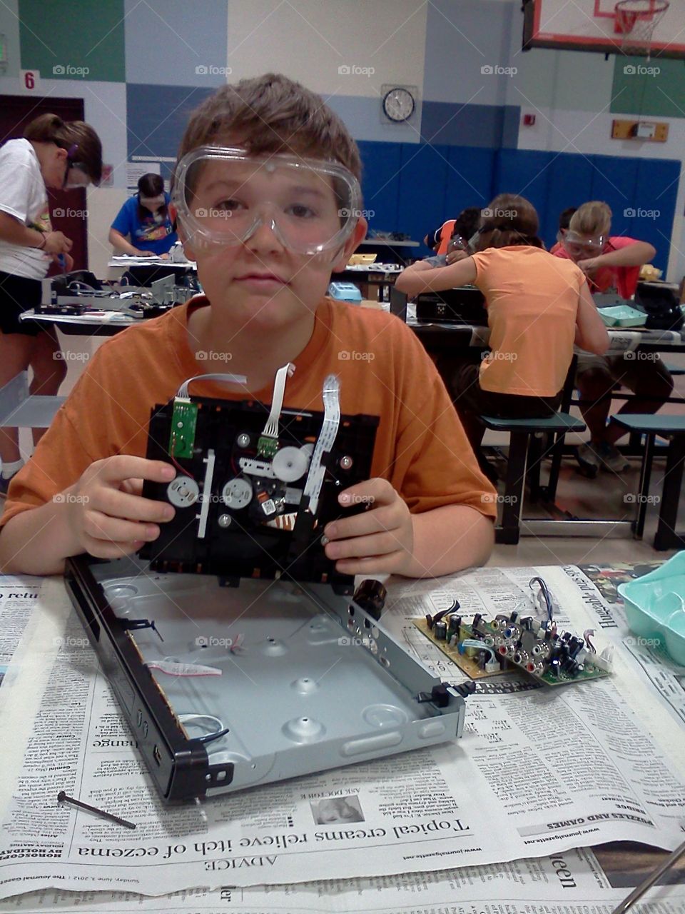 A boy holding electronic parts from dismantling a DVD player or vcr.