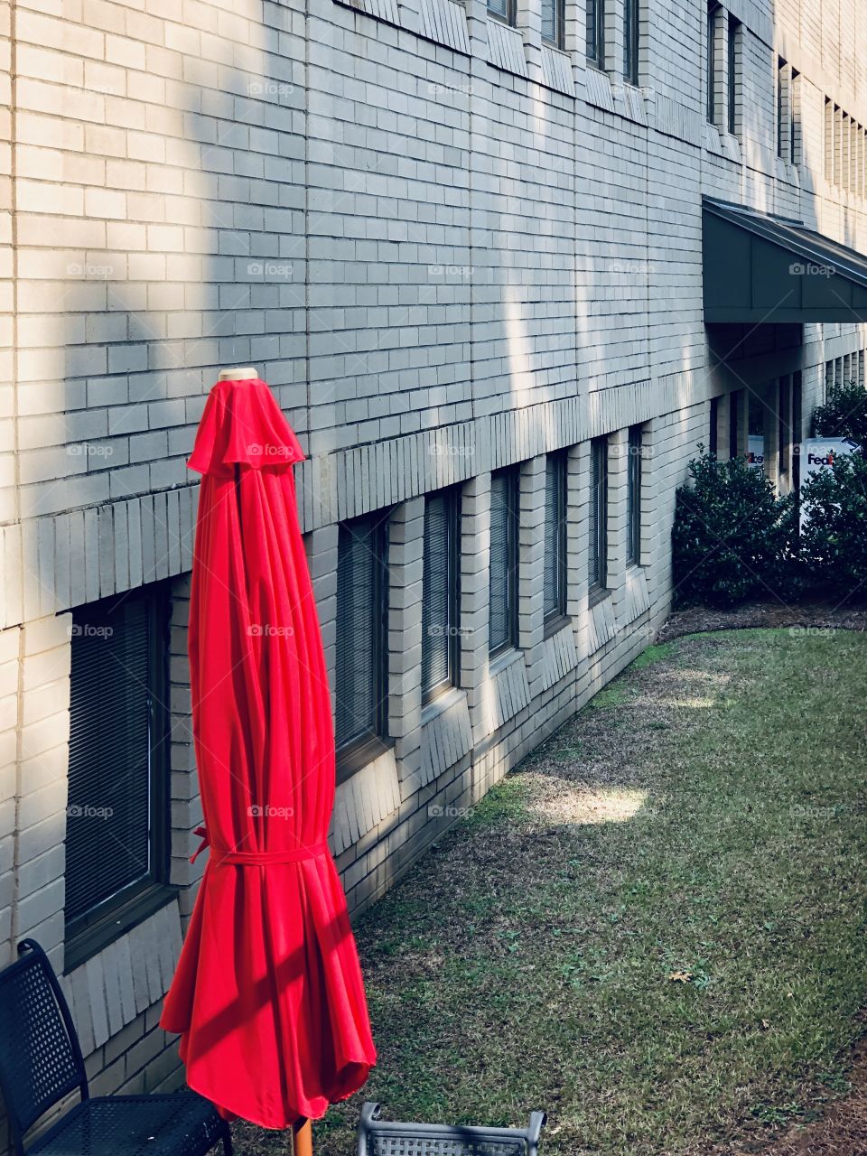 Red outdoor umbrella in courtyard of brick office building 
