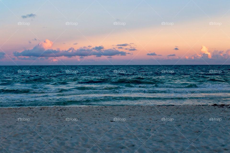 a beautiful sunset over the water: taken on a sandy beach in florida and perfectly captures the peaceful power of the sea