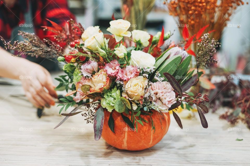 DIY autumn flower arrangement bouquet in pumpkin, florist at work, floristry studio