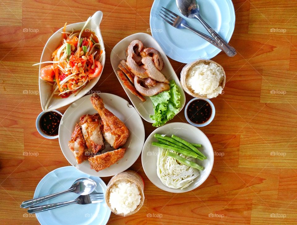 Papaya salad, grilled chicken, pork, vegetables, sticky rice and sauce. Delicious food of Thailand.