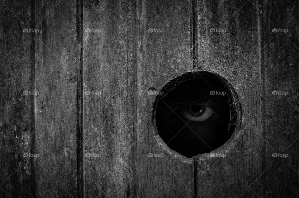 Creepy eye looking through wood 