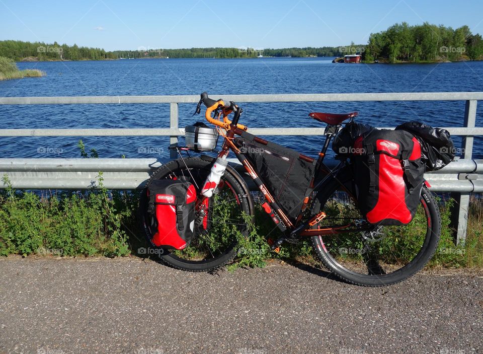 Lappeenranta, Finland - June 29, 2015: Adventure bike with mountain bike & touring bike capabilities and red panniers and other touring and camping gear attached to the bike by a lake Saimaa near Lappeenranta in Eastern Finland.