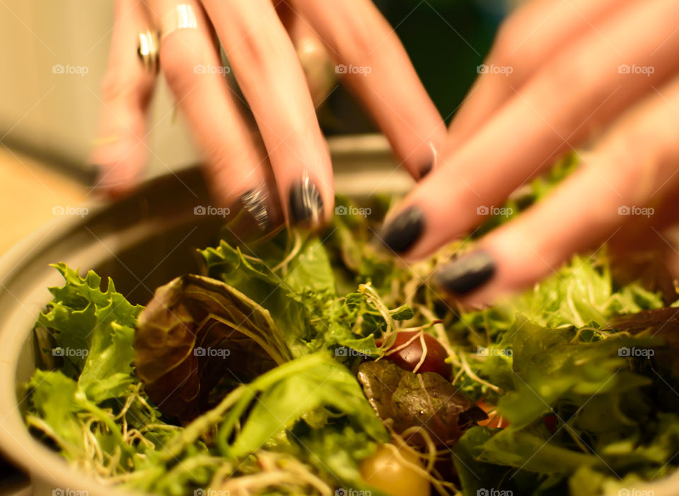 Closeup of hands in motion adding healthy ingredients to spinach, lettuce and sprout salad 