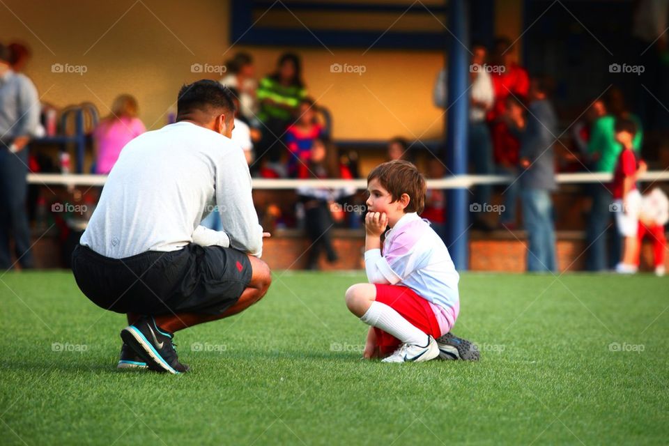 Football coach giving instructions to young kid player