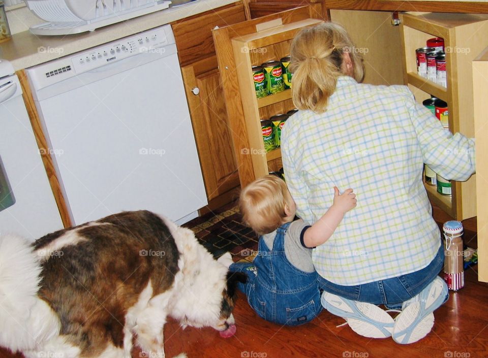 Little Grandson hugging his Grandma while they put away items in the cupboard in the kitchen!