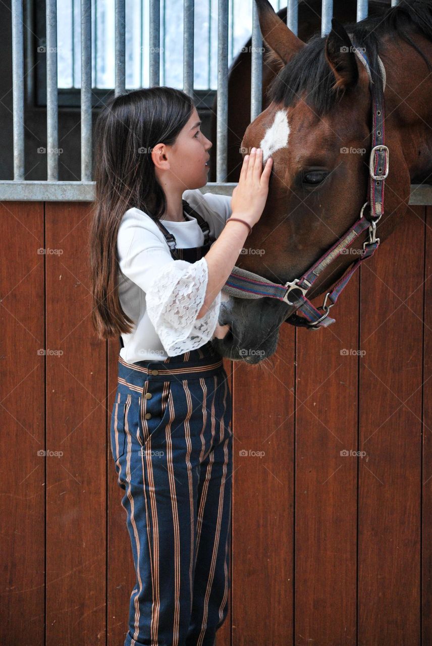 Teenage girl tending to her horse in a stable