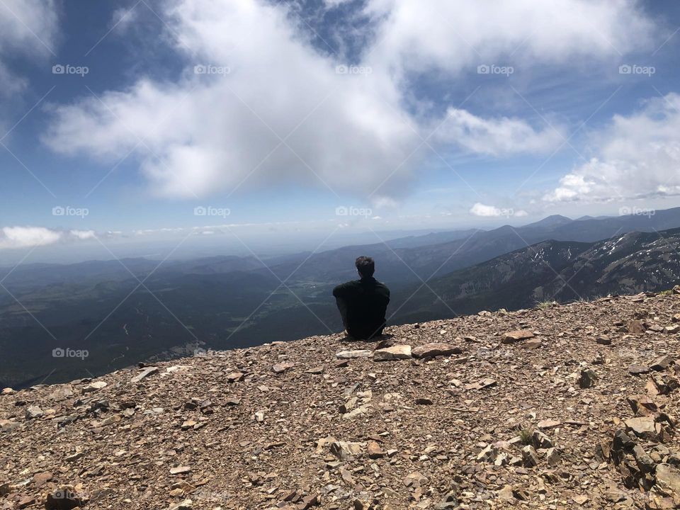 Man sitting on mountain top with cloudy skys in New Mexico