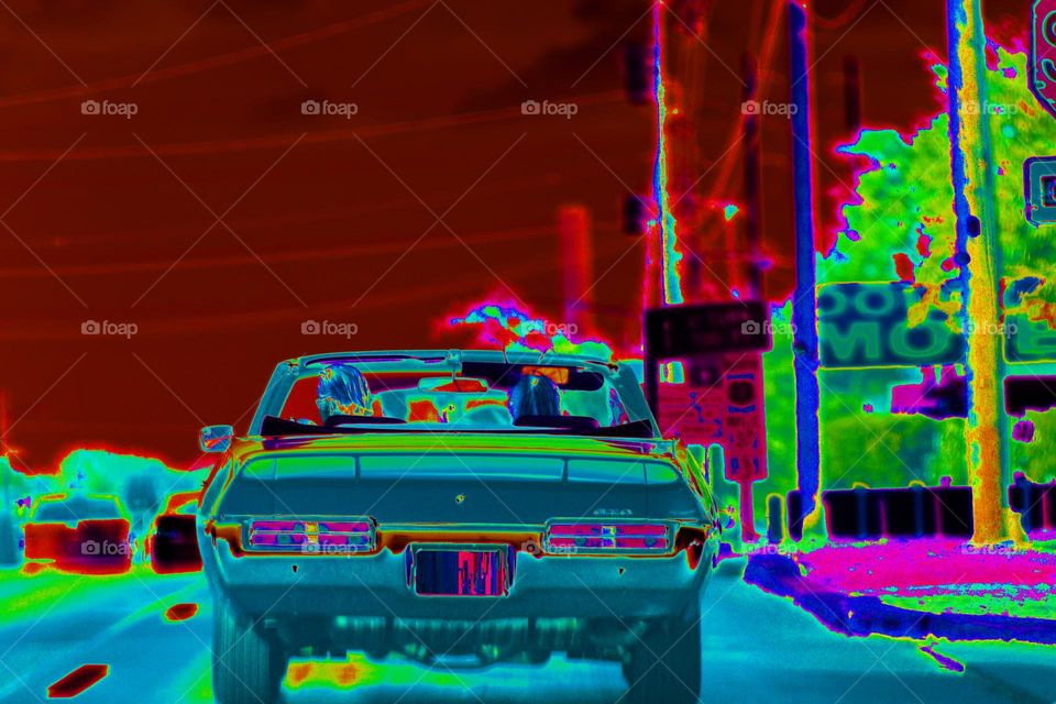 A couple cruises down the route 1 interstate in a classic drop top convertible GTO.