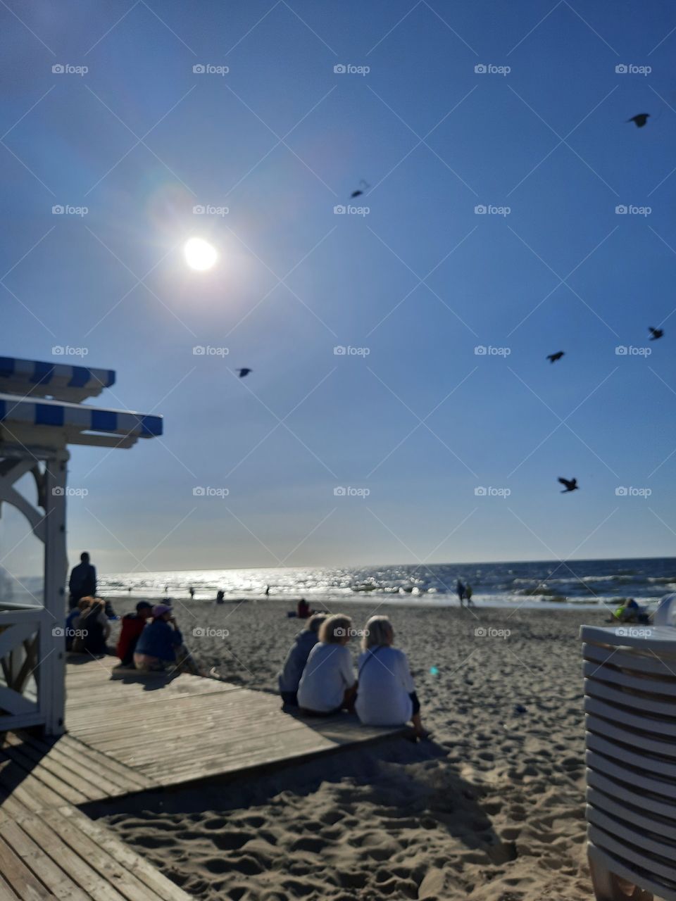 summer  beach with bitds flying and People sitting