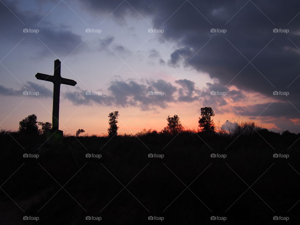 Cross on landscape at sunset