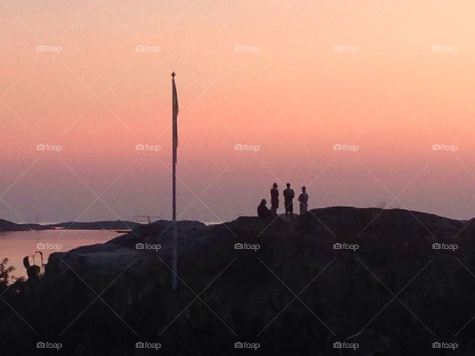 Small group of people on rock in sunset