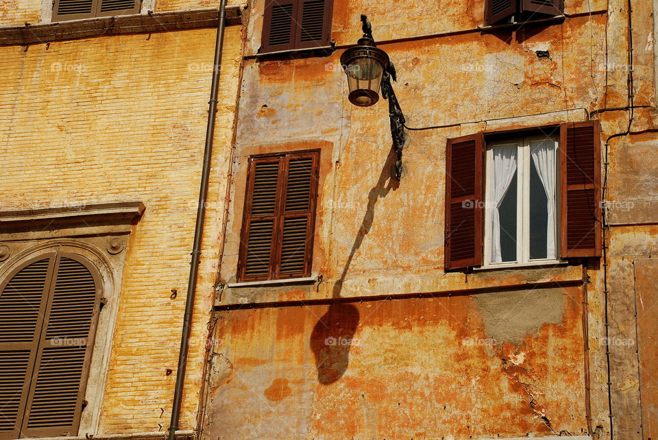 Hi noon in Rome. Shadow of an anxious at lamppost against an old Roman building