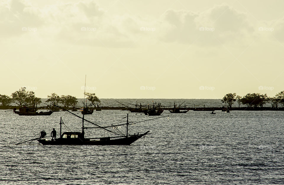 Fisherman on the boat and fishing boats parked on the sea coastline at Laem thian beach , Chumphon in Thailand.