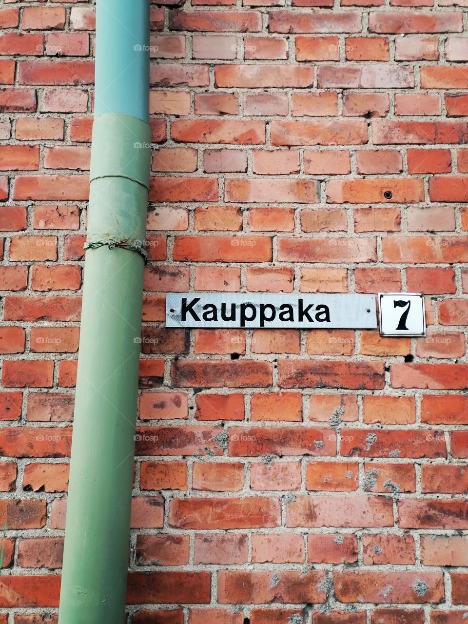 Finnish old street sign on a brick wall. It should read Kauppakatu (Shopping Street) , but it is missing 2 letters.