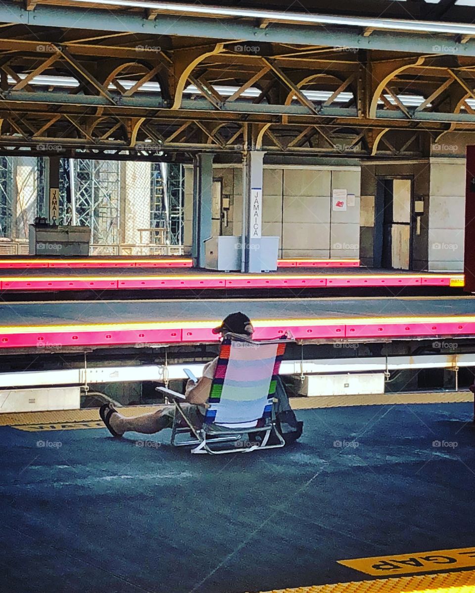 Person lounging on beach chair on train platform