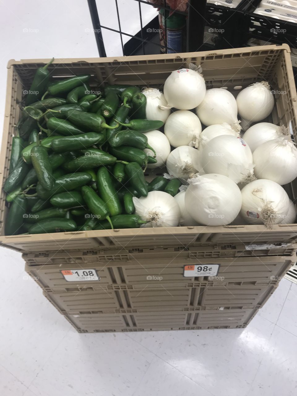 Green jalapeños peppers and white onions on sale at the grocery store