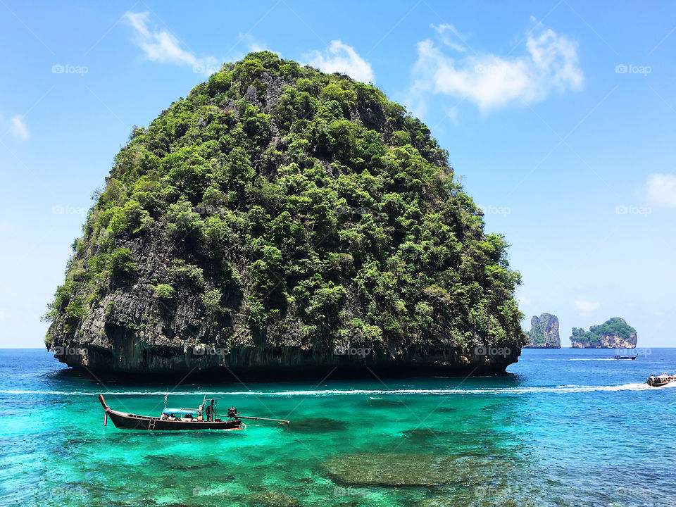 Thai boat near the green tropical island in turquoise sea water in Thailand 