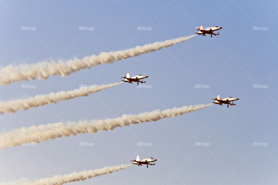 Four planes in the sky performing tricks with the smoke