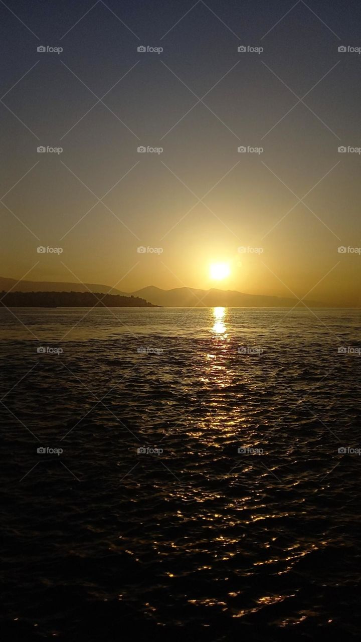 Moments before the sun disappears behind those mountains where everything is so calm and quiet. A beautyful view in the middle of the sea...