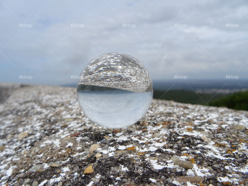 Crystal ball standing on a rock looking deep into the landscape 