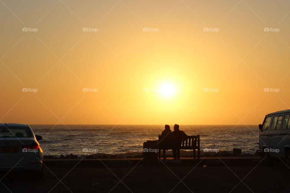 Couple at sunset. A couple sitting on a bench at a beautiful sunset