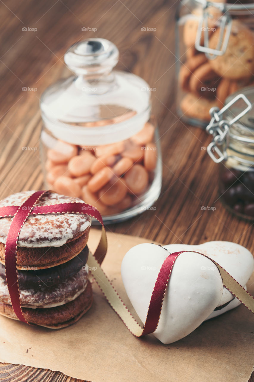 Gingerbread cookies, candies, cakes, sweets in jars on wooden table