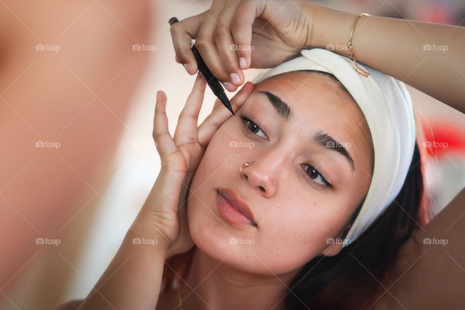 Beautiful smiling young woman is putting her makeup on