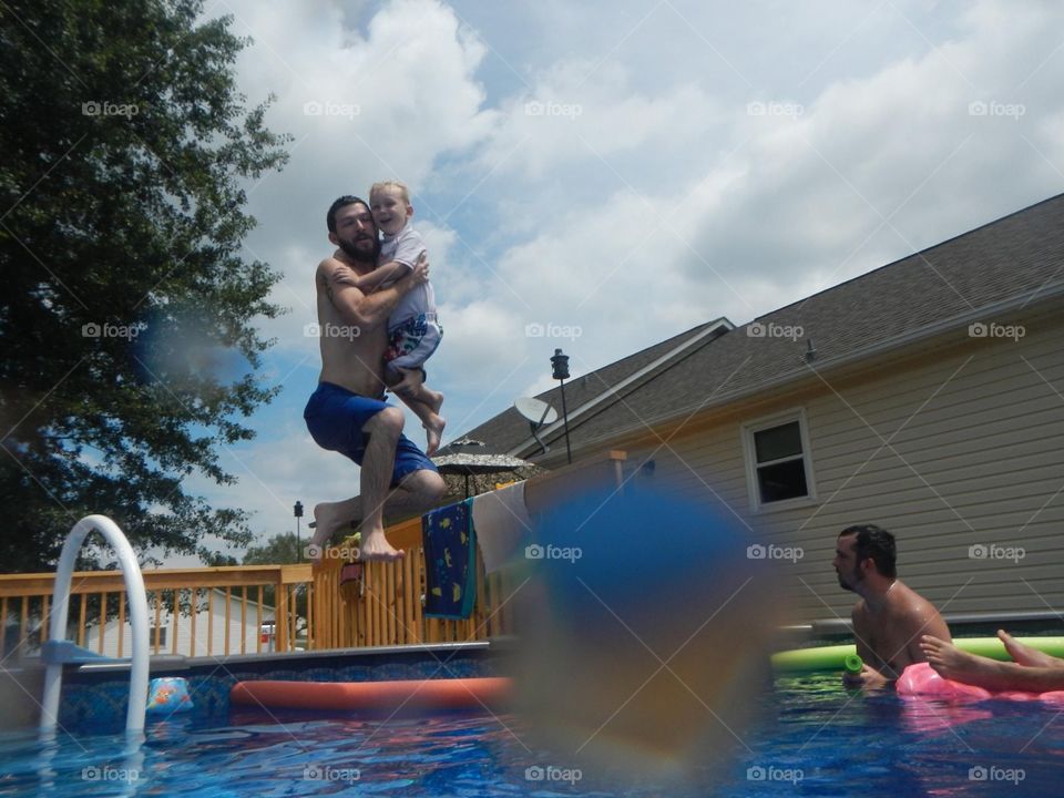 Father and son jumping in the swimming pool