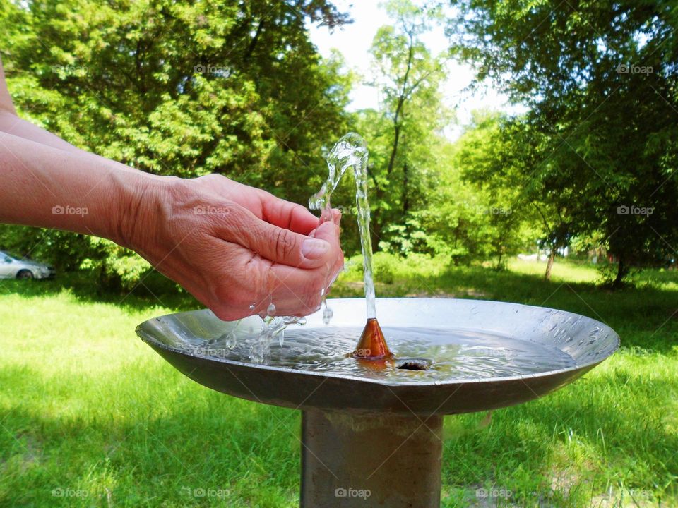 female hands and drinking water fountain