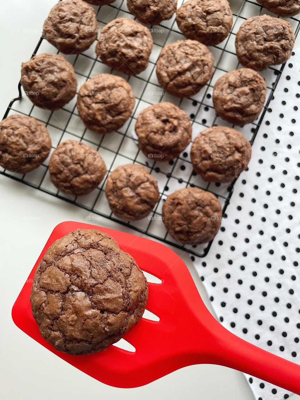 Placing freshly baked brownie cookies on a cooling rack, making brownie cookies with children, baking homemade brownie cookies from scratch