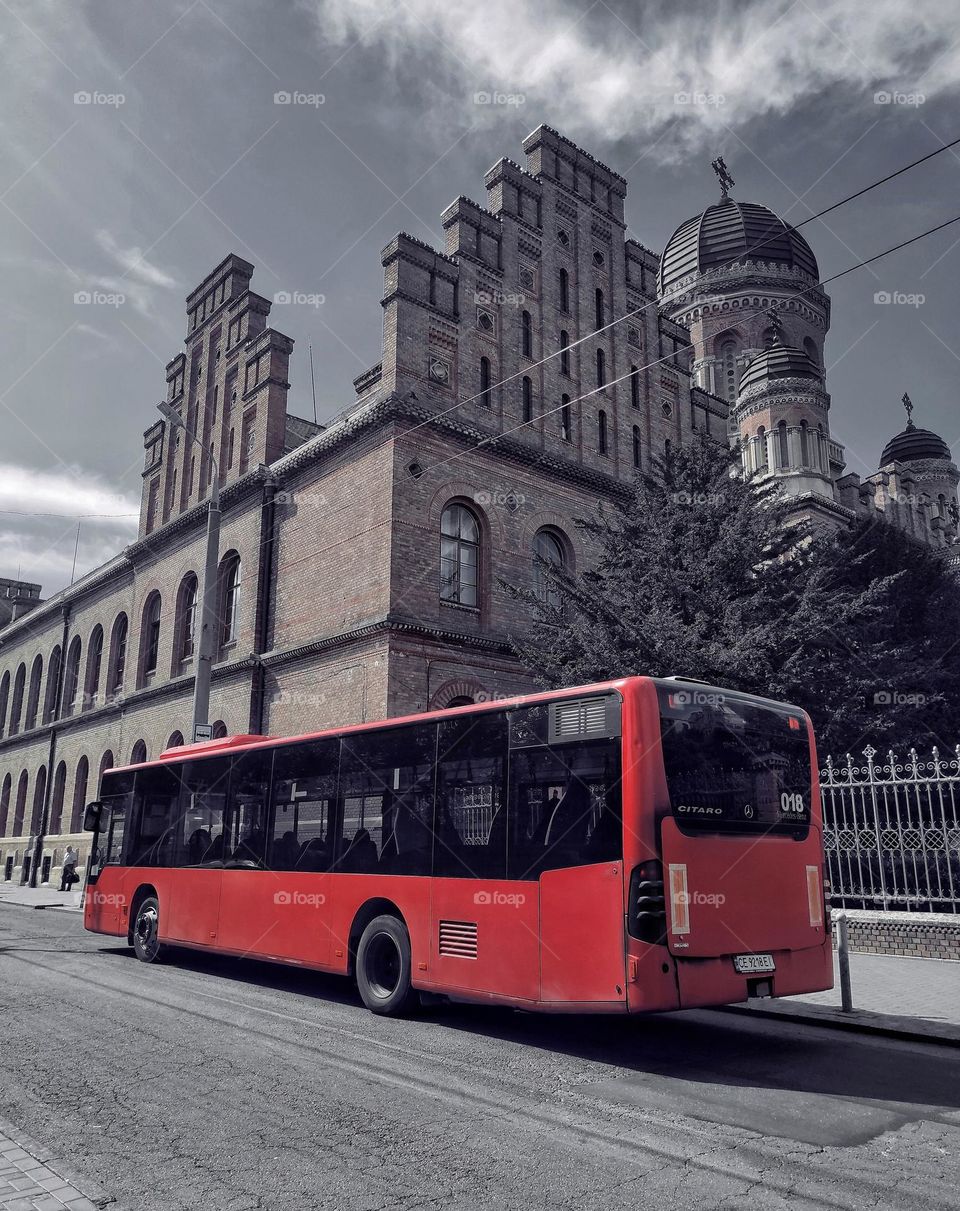 Red bus at the bus stop against the backdrop of the university