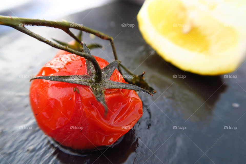 Mini tomato on a plate with sliced lemon.