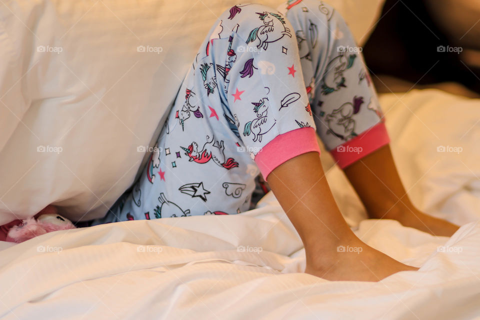 Girl's legs in pajama pants with unicorns and rainbows