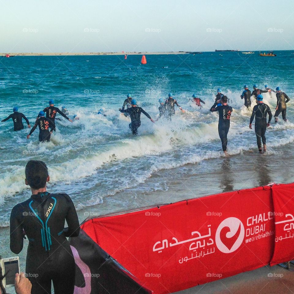 Into the waves. Triathletes diving into the swimming race