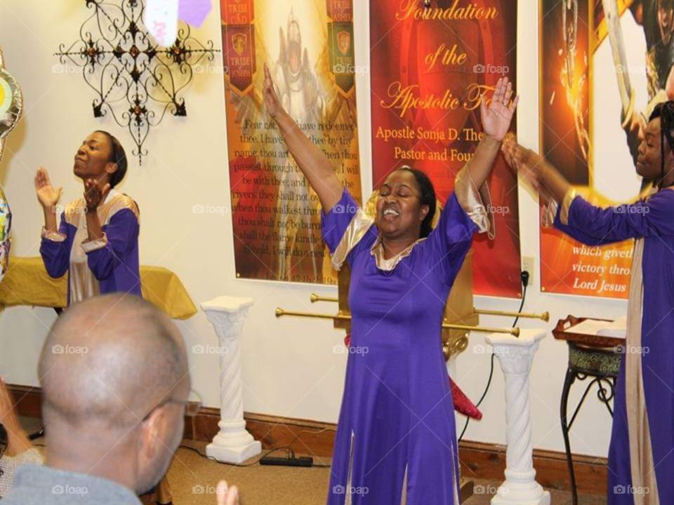 Women celebrating God in dance at church, with their royal purple dress with gold trim on the cuff and neckline