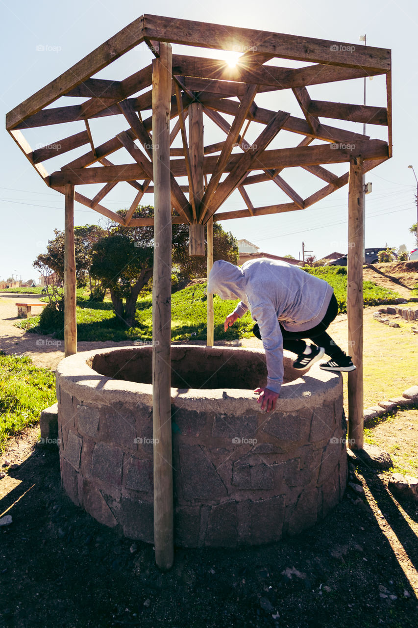 Street photography of a young man jumping into a hole that represents the way out of the problems of the life 