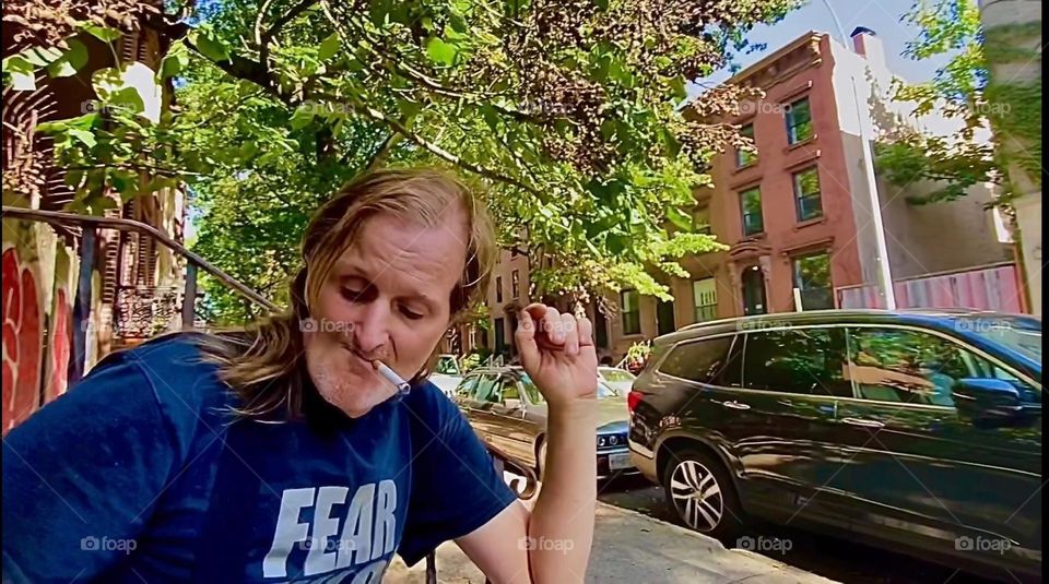 „Timothy Trespas“, my longtime partner and friend is sitting on our favorite stoop on „Waverly Av” off “Fulton St” in “Clinton Hill”, Brooklyn conversing and having a smoke. 2022. Hypnotic Productions