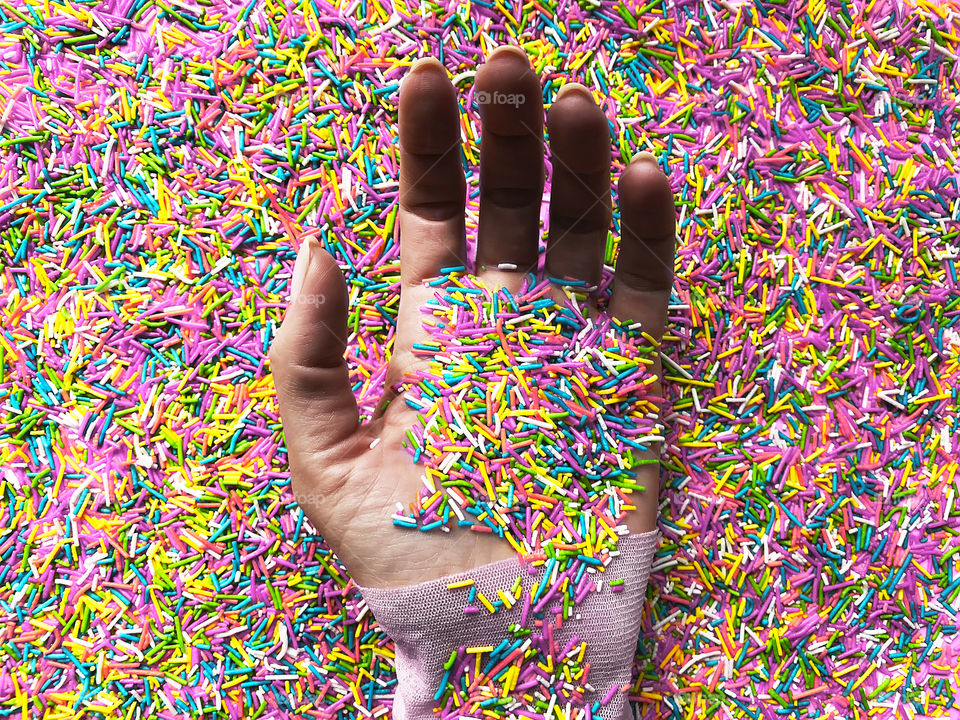 Female hand among the colorful pastel sprinkles 