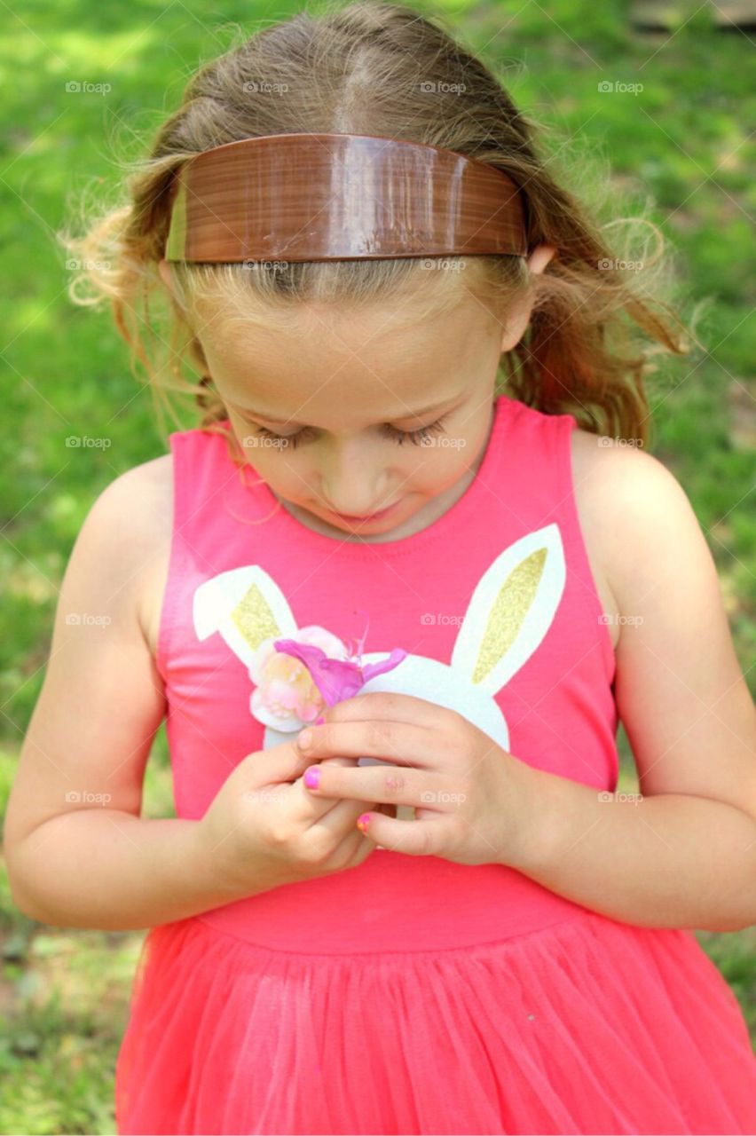 Little girl looking at flower