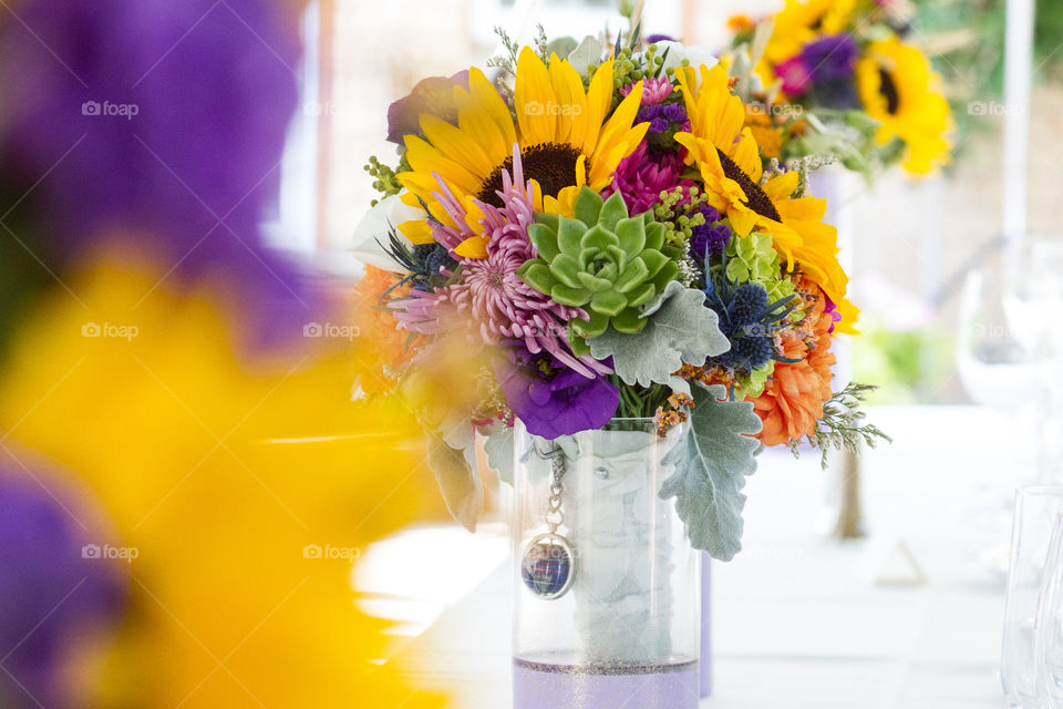 A bride's wedding bouquet in a vase at a reception with a globe trinket 