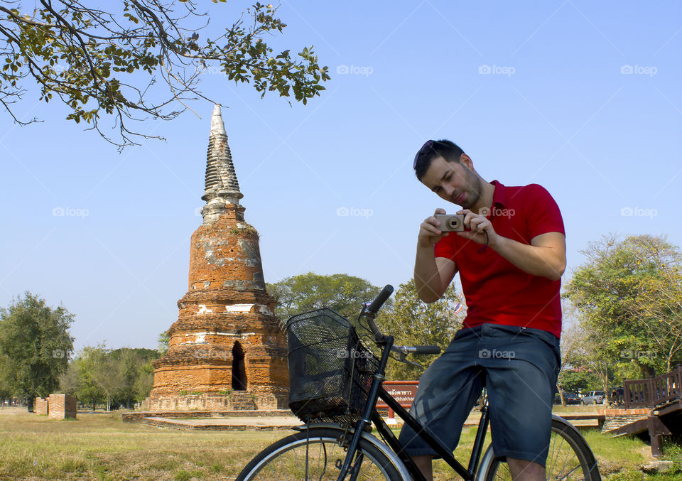 Man sitting on bicycle and capturing photo from camera