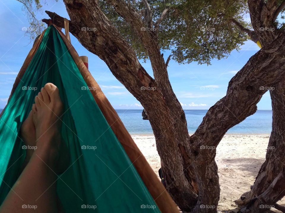 Relaxing on a green hammock at the beach, facing the sea